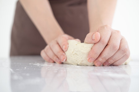 Female hands making dough for pizza . Woman kneading dough on table sprinkled with flour.Making bakery by female hands at home.の写真素材