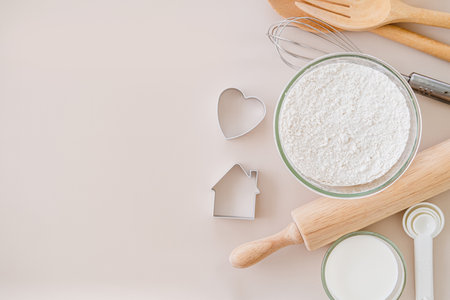 Frame of baking and cooking bread pastry or cake ingredients and cooking utensils , flour milk eggs. whisk , cookies cutter and flour sieve on bright  background with copy space for text, flat layの写真素材