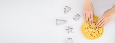 Woman preparing gingerbread cookies on white table at kitchen . Female hands cutting ginger dough with cutter to making cookies for winter holidays.top view.copy space. Bannerの写真素材