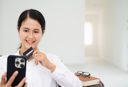 Happy middle age woman sitting with credit card and smart phoneの写真素材