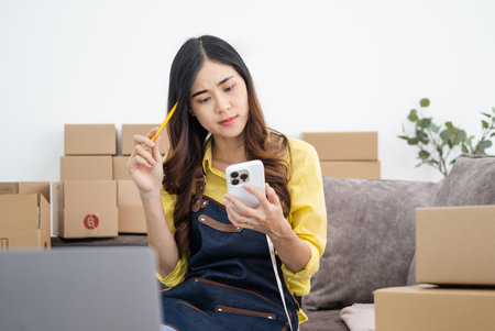 Asian woman think hard serious working laptop computer at home selling online start up small business owner, e-commerce ideas concept.の写真素材