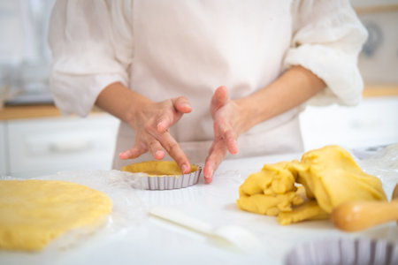 Hands making tart using cookie cutter to cut out pastry dough closeup. Kitchen stuff tools utensils. cooking and home concept - close up of female hands making tart from fresh dough at homeの写真素材