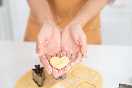 Cropped image of hands cutting cookies of dough while baking in kitchen .Making for homemade biscuits. On the table is dough and a set of cookie molds with other kitchen equipment.の写真素材