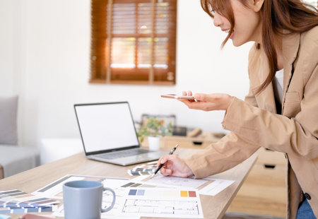 Designer working in office and making call on mobile phone.の写真素材