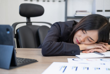 Tired businesswoman sleeping on the desk, in front of the computer screen.の写真素材