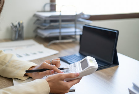 Close up Business woman using calculator and laptop for do math finance on wooden desk in office and business working background, tax, accounting, statistics and analytic research conceptの写真素材