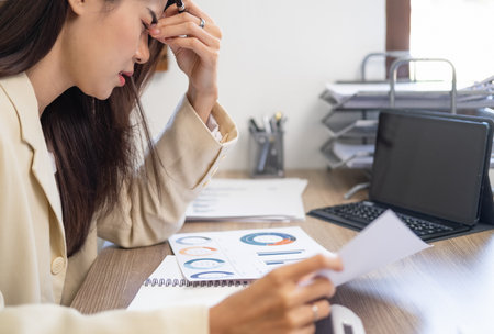 Tired teen girl rubbing dry irritable eyes feel eye strain tension migraine after computer work, exhausted young Asian woman student relieving headache pain, bad weak blurry vision, eyesight problemの写真素材