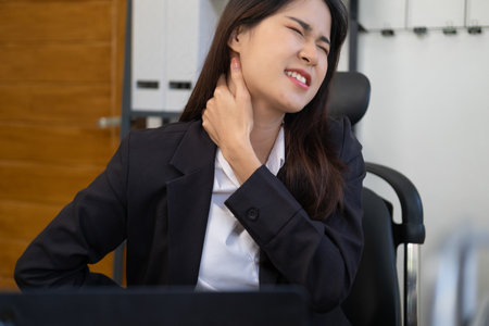 Business woman overwork on laptop computer and neck pain with at work in office, girl stress and illness chronic with office syndrome, health and emotion concept.の写真素材