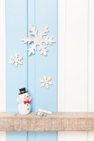 Front view of snowman and wooden snow flake on shelf over blue white wall background . -Winter decorationsの写真素材