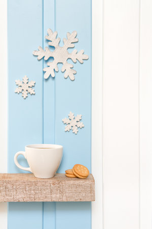 Winter decorations - Front view of Coffee cup with wooden snow flake and pines on shelf over blue white wall background .の写真素材