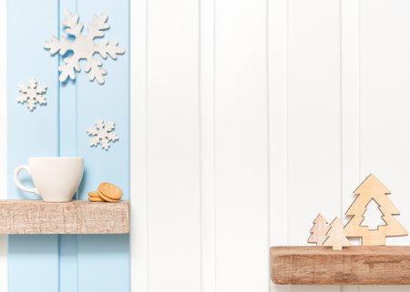 Winter decorations - Front view of Coffee cup with wooden snow flake and pines on shelf over blue white wall background .の写真素材