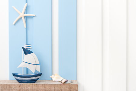 Summer sea decoration background - Front view of sailboat , starfish and seashell on wooden shelf over blue white wall .の写真素材