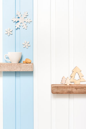 Winter decorations - Front view of Coffee cup with wooden snow flake and pines on shelf over blue white wall background .の写真素材