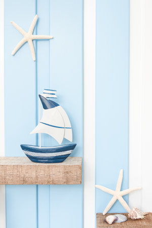 Summer sea decoration background - Front view of sailboat , starfish and seashell on wooden shelf over blue white wall .の写真素材