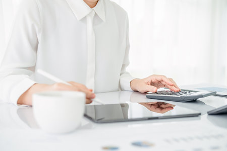 Modern business woman using calculator and tablet  in workstation.の写真素材