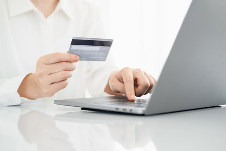 Woman hand holding credit card and using laptop at home, online shopping and paying bills, Payment method.の写真素材