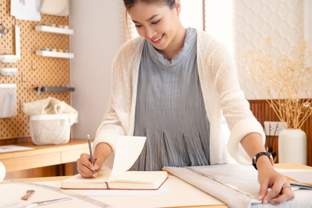 Fashion Designer Cutting Tailor Made Concept.Attractive young asian woman fashion designer in office or tailor shopの写真素材