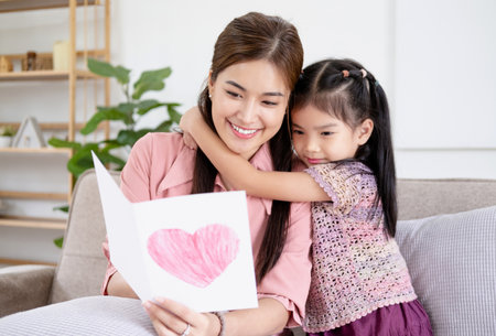 Happy mother's day! Child daughter congratulates mom and gives her card. Mum and girl smiling and hugging. Family holiday and togetherness.の写真素材