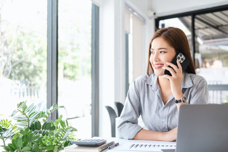 Close up Young Office Woman Talking to Someone on her Mobile Phone While Looking Into the Distance with Happy Facial Expression.の写真素材