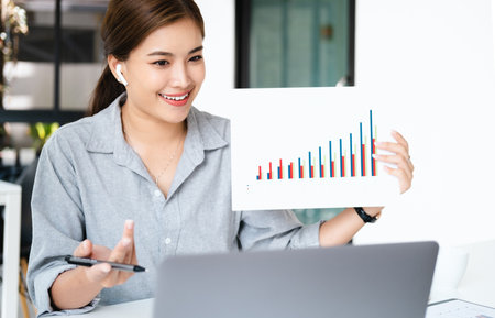 business woman talking about sale report in video conference. Asian team using laptop and tablet online meeting in video call.Working from home, Working remotely and Social isolation.の写真素材