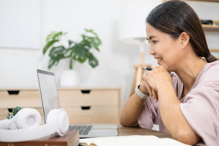 Happy asian woman  in online learning , enjoying watching educational webinar on laptop. Smiling...