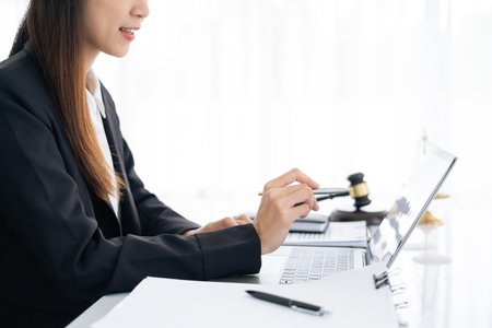 advice and justice concept. Justice scales, justice hammer and Litigation and Litigation document, female lawyer holding pen, working legal law with use laptop at lawyer office.の写真素材