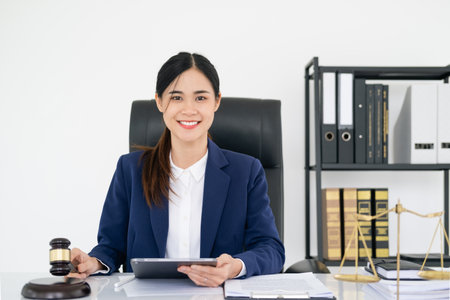 Beautiful woman lawyer working and gavel, tablet, laptop in front, Advice justice and law concept.の写真素材