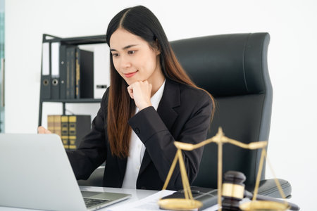 Justice and law concept. smiling Female lawyer in office with the gavel working with digital tablet computer docking keyboard on white table.の写真素材