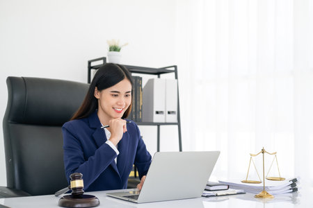 advice and justice concept. Justice scales, justice hammer and Litigation and Litigation document, female lawyer holding pen, working legal law with use laptop at lawyer office.の写真素材