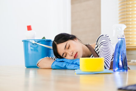 Tired and exhausted woman cleaning house in kitchen room, frustrated with doing much work about the house resting for a minute  after finishing work, taking breakの写真素材