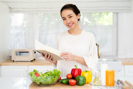 Woman reading recipe for simple summer salad in cookbook. Simple healthy food conceptの写真素材