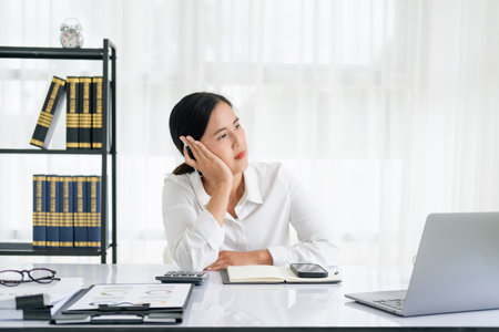 thoughtful Asian business woman executive manager wearing shirt working in modern office, taking notes and thinking of professional plan, project management, considering new business ideas.の写真素材