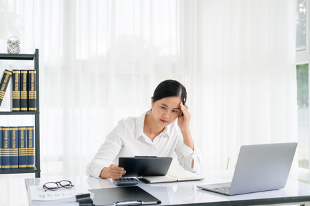 asian business woman manager accounting analyst checking bills, analyzing sales statistics management, taxes financial data documents or marketing report papers working in office using laptop.の写真素材