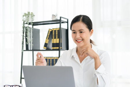 Asian female entrepreneur working remotely from home office using modern computer.Young cheery happy positive cute beautiful business woman sit in home office using laptop computer.の写真素材