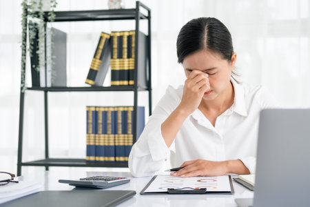 Asian women are stressed while working on laptop, Tired asian businesswoman with headache at office, feeling sick at work, copy spaceの写真素材
