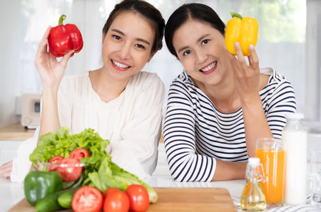 healthy eating, family friendship and people concept - Female Friends Enjoying Fresh Salad in kitchen and Having Fun. cooking vegetable salad for dinner at home kitchenの写真素材