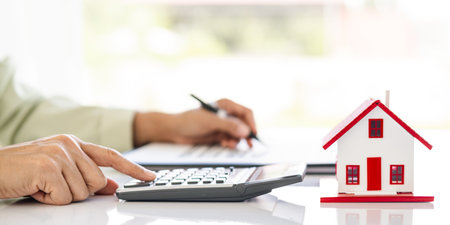 Hand of Business people calculating interest, taxes and profits to invest in real estate and home...