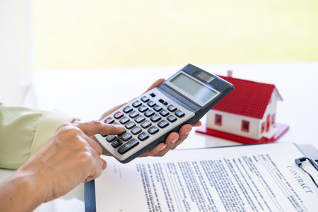 Hand of Business people calculating interest, taxes and profits to invest in real estate and home buyingの写真素材