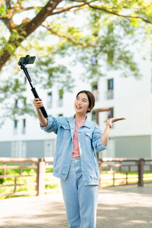 Tourists in the city taking selfies on university street. Asian girl taking selfies while walking on the street in summer happily with her mobile phone. Travel and summer vacation lifestyle concept.の写真素材