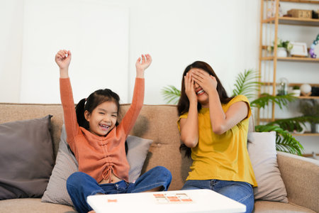 Asian beautiful loving mom playing game with daughter in house. Attractive woman parent spend free leisure time with young little girl child spend time learn and develop skill with kid's toy.の写真素材