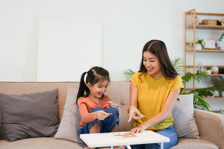 Asian beautiful loving mom playing game with daughter in house. Attractive woman parent spend free leisure time with young little girl child spend time learn and develop skill with kid's toy.の写真素材
