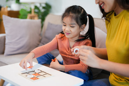 Asian happy family of little daughter play tic tac toe in home. Mother or mom young woman loving parent having fun play game  in living room. Hobbie leisure conceptの写真素材