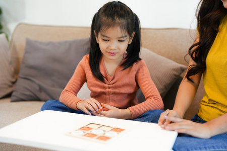Asian beautiful loving mom playing game with daughter in house. Attractive woman parent spend free leisure time with young little girl child spend time learn and develop skill with kid's toy.の写真素材