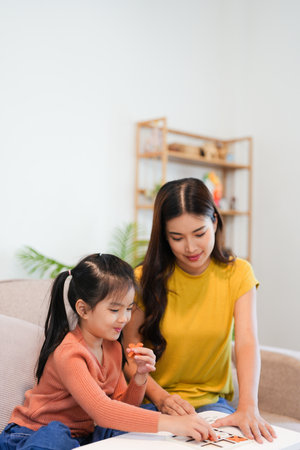 Happiness mother and daughter sit on sofa in the house  playing game together, family joyful together in the house on holidayの写真素材