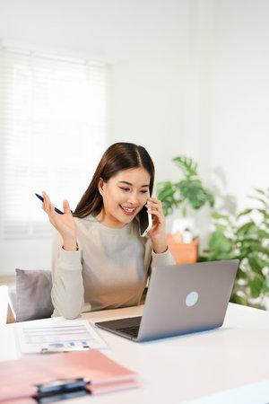 Happy young Asian business woman with a smile using smartphone at the office.の写真素材