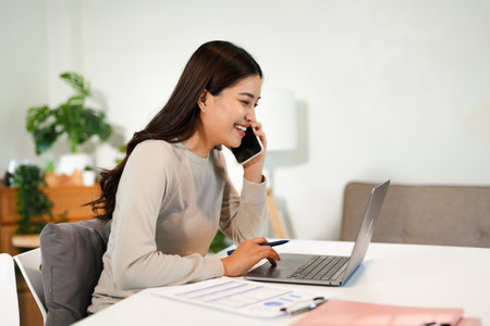 Asian business woman making a phone call and smiling indoorの写真素材