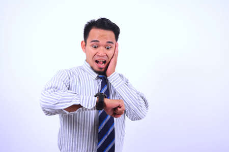 businessman looking at his watch with a surprised expressionの写真素材