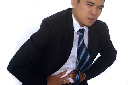 Photo image of a handsome asian businessman suffering from abdominal pain isolated on white