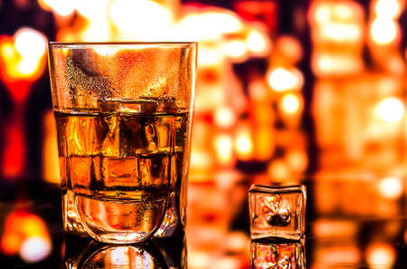 Glass of scotch whiskey and ice on the background of the barの写真素材