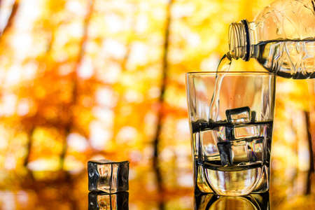 Pouring water into glass with ice cubeの写真素材
